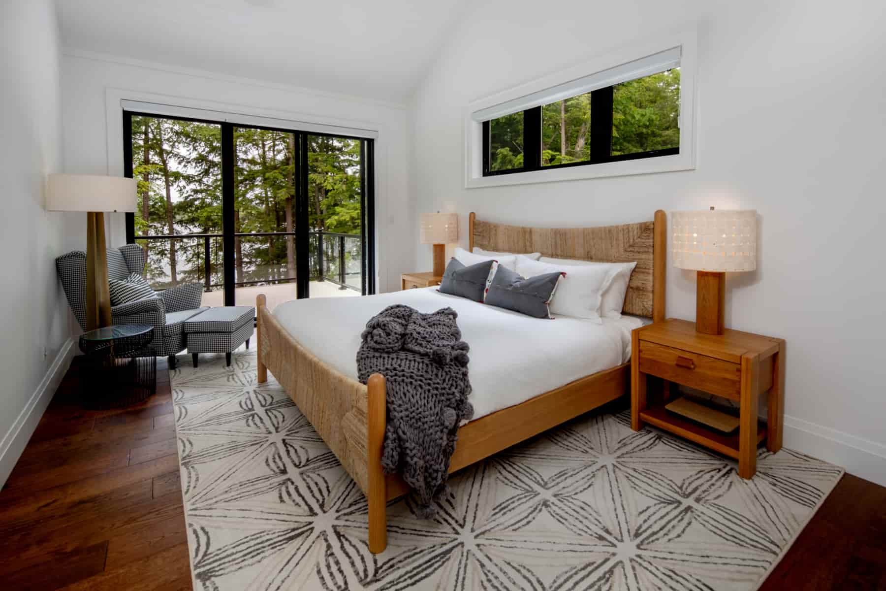  Elegant bedroom with a bed, nightstands, and windows, crafted by Ballantyne Builds in the picturesque Lake Muskoka.