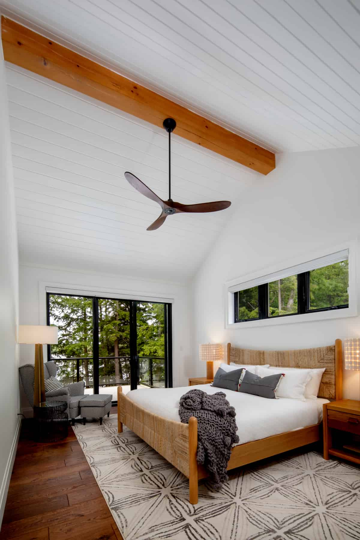 Cozy bedroom with a ceiling fan and wooden flooring, situated in Lake Muskoka, designed by Ballantyne Builds