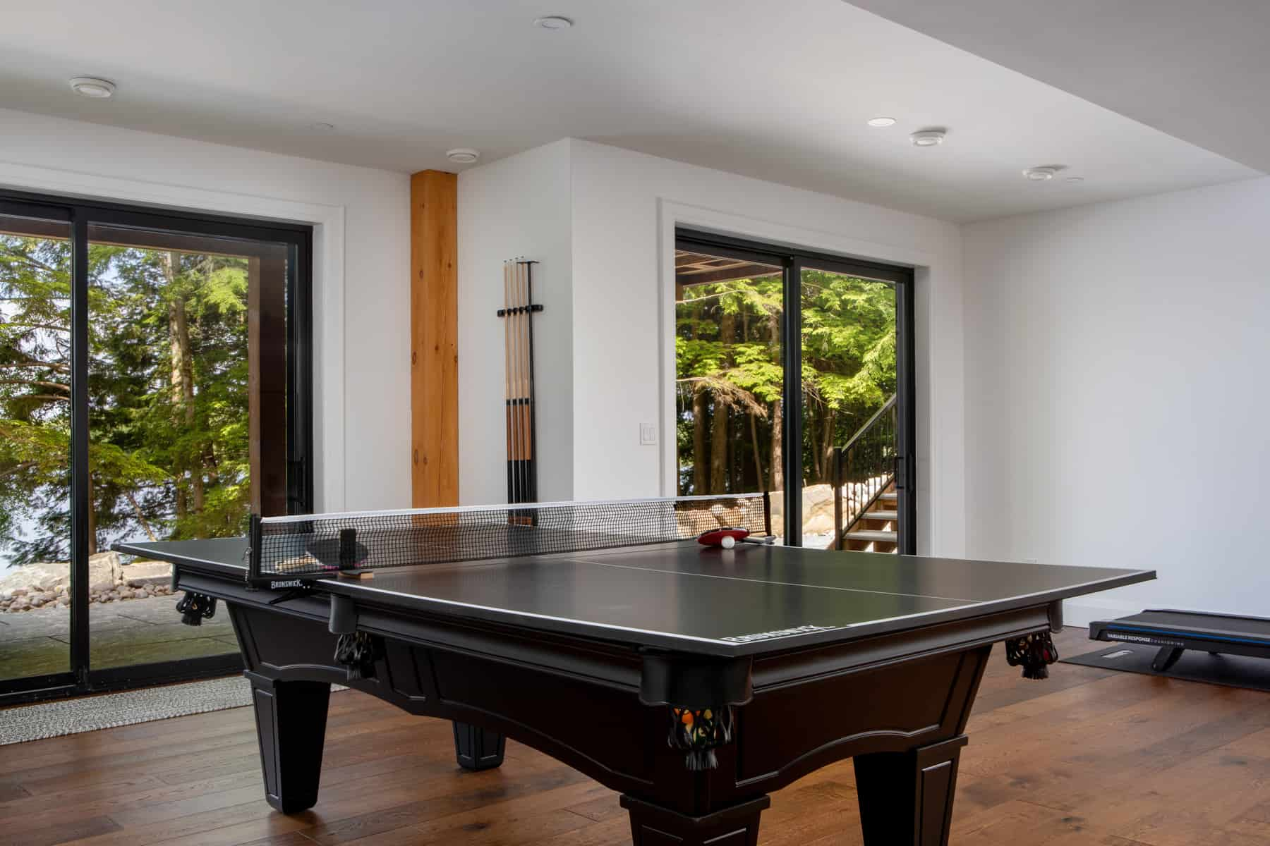 A ping pong table set in a room featuring a sliding glass door, located in Lake Muskoka by Ballantyne Builds.
