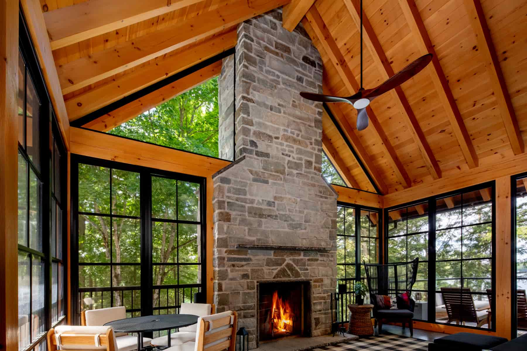 A large living room with a cozy fireplace and elegant wood floors, situated in Lake Muskoka, crafted by Ballantyne Builds.
