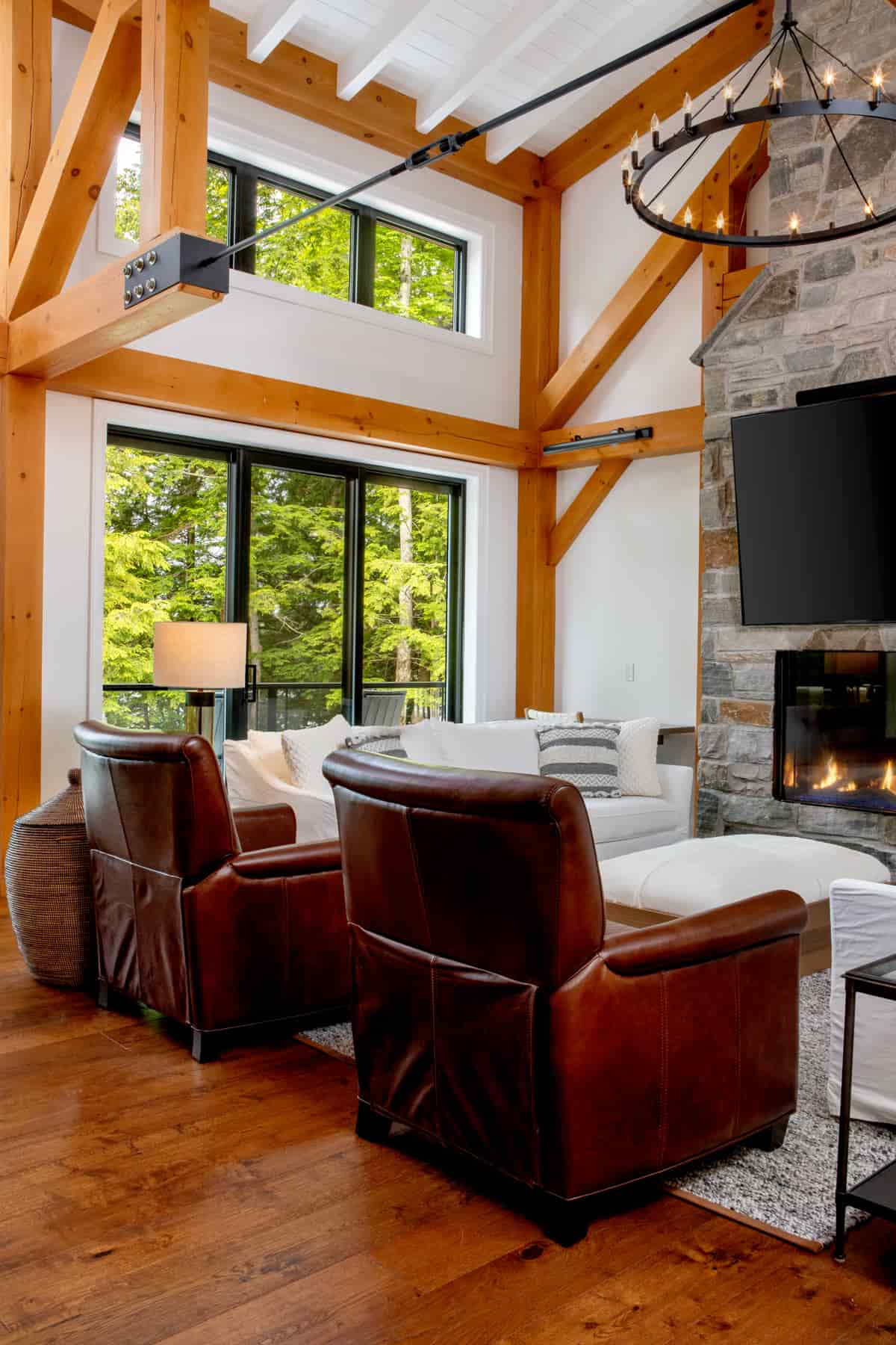  Inviting living room with a fireplace and rustic wood beams, in Lake Muskoka | Ballantyne Builds.