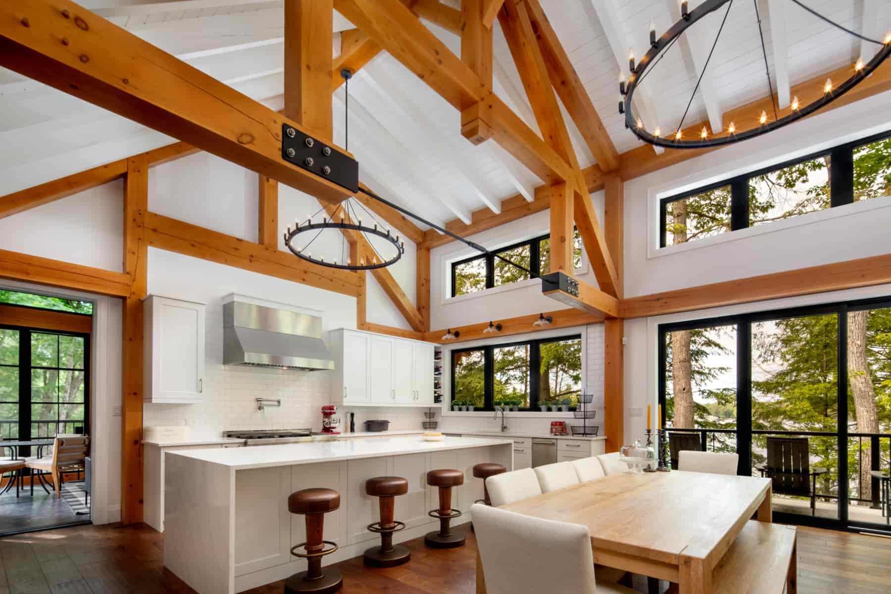 A modern kitchen and dining area showcasing wood beams, created by Ballantyne Builds in the scenic Lake Muskoka.