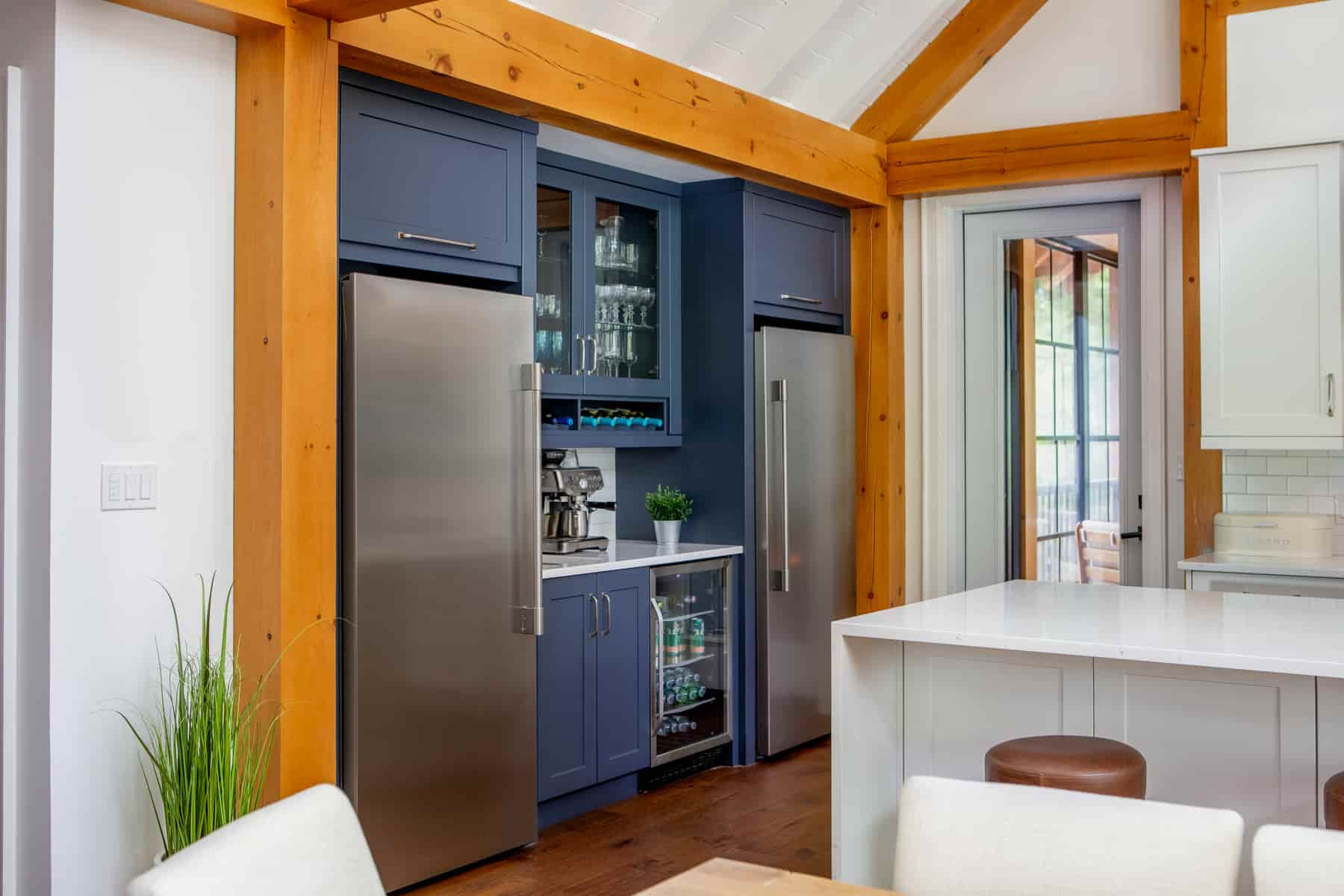 A modern kitchen featuring a refrigerator and a dining table, located in Lake Muskoka by Ballantyne Builds.