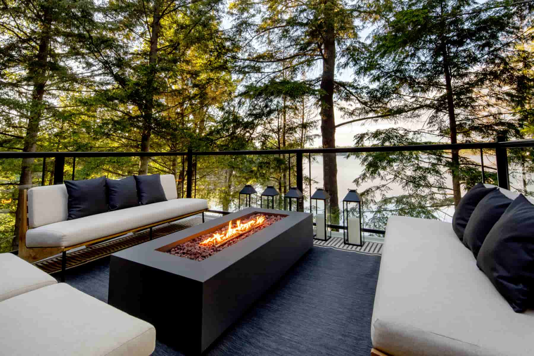  Elegant patio with inviting couches and a fire pit, showcasing stunning views of Lake Muskoka from Ballantyne Builds.