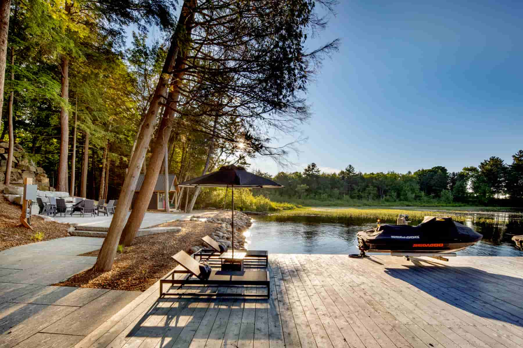 A serene dock at Lake Muskoka featuring chairs and a jet ski, showcasing the beauty of Ballantyne Builds.