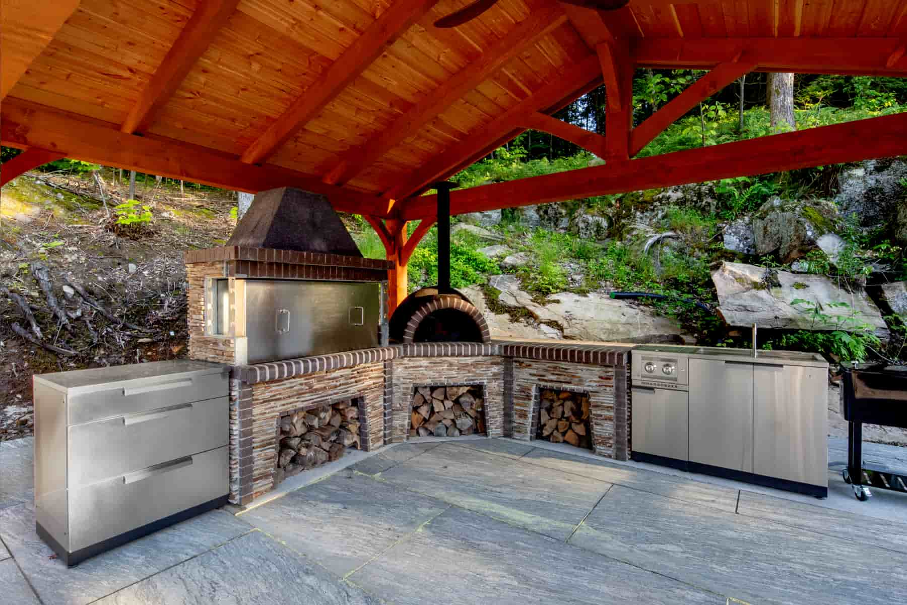  An outdoor kitchen featuring a grill and oven, designed by Ballantyne Builds at Lake Muskoka, showcasing modern amenities