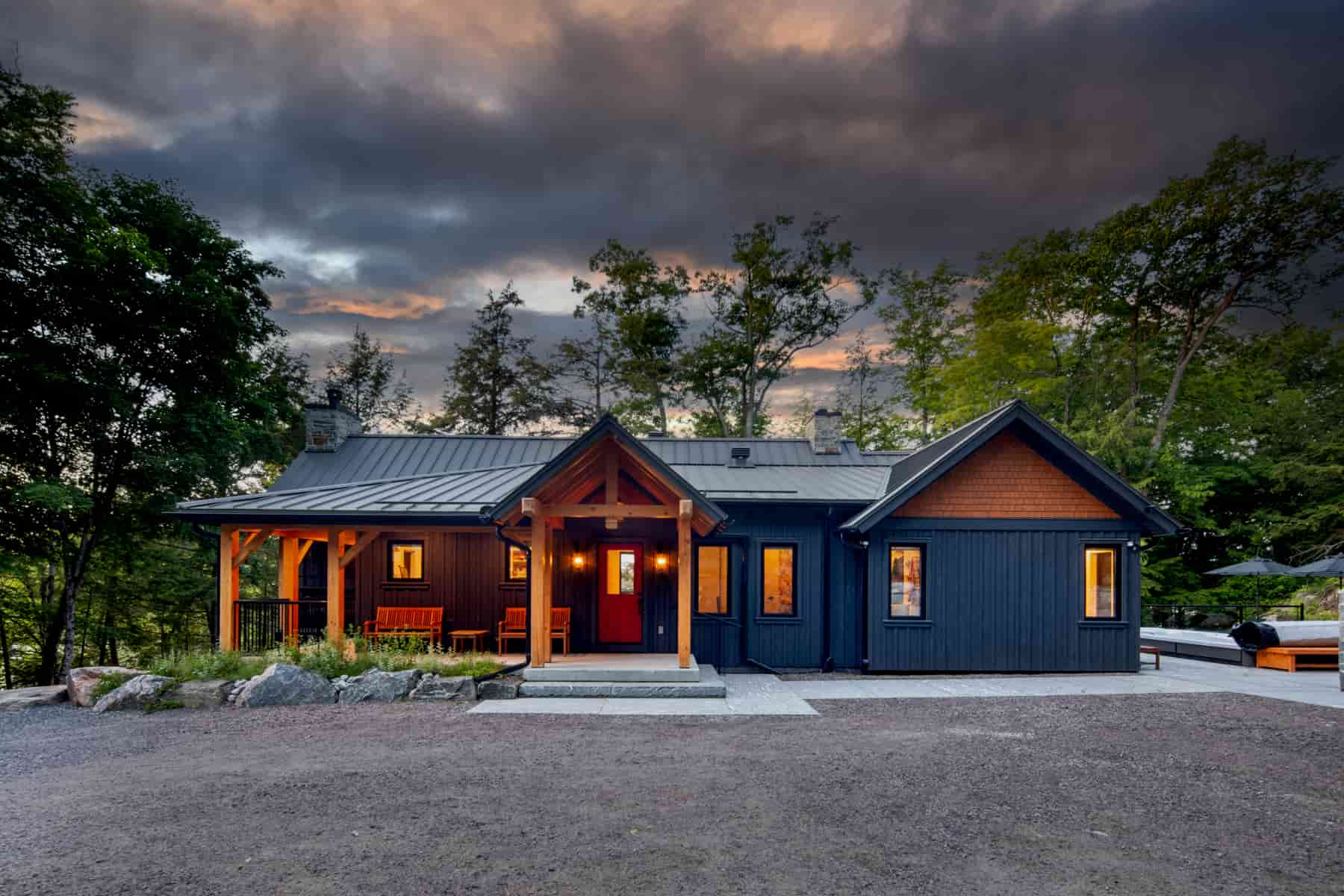 A blue house stands under a dark, cloudy sky, creating a striking contrast in the scene Lake Muskoka | Ballantyne Builds