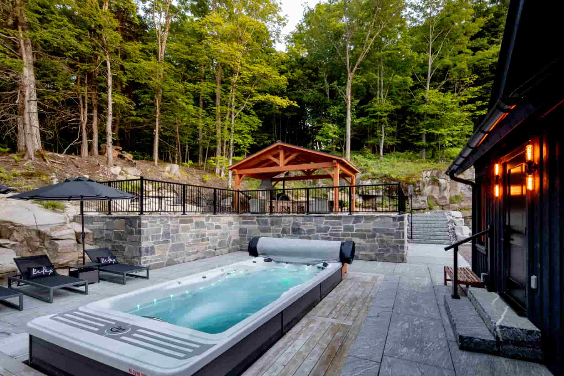 A luxurious hot tub in a tranquil backyard setting, highlighting the craftsmanship of Ballantyne Builds at Lake Muskoka.