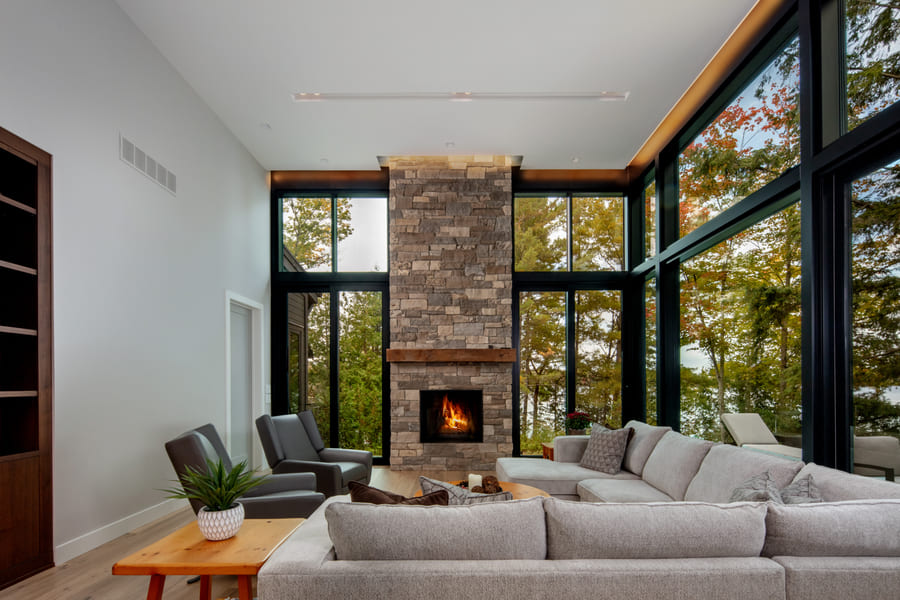 Living Room View with Stone Fireplace and Two Full Glass Walls | Ballantyne Builds