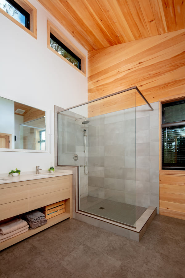 Custom large full bathroom, custom wooden vanity, glass walk-in shower, windows, tiled floor | Ballantyne Builds